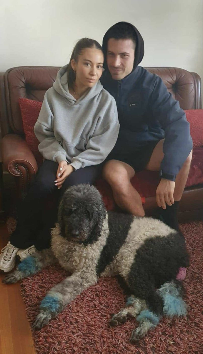 Ruby and her partner sitting together with their large curly-coated dog